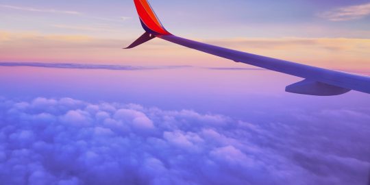 person in a plane flying at high altitude taking photo of left airplane wing during daytime